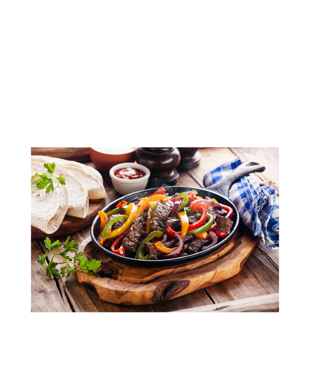 Steak and vegetable dish on a wooden board with a white background